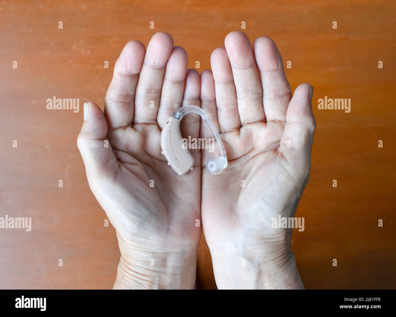 Elektronisches Hörgerät im Ohr einer alten asiatischen Frau mit totaler Taubheit. Stockfoto