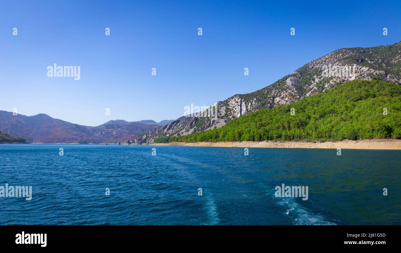 Blick auf das grüne Wasser des Oymapinar Dam mit grünen Bäumen am Ufer Stockfoto