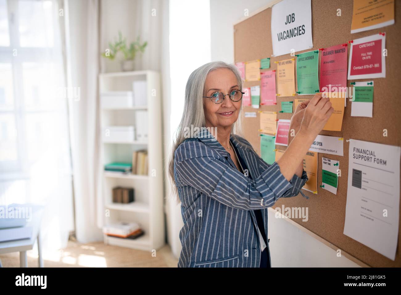 Mitarbeiter im Jobcenter, die offene Stellen auf dem Jobnotizbrett anheften. Stockfoto