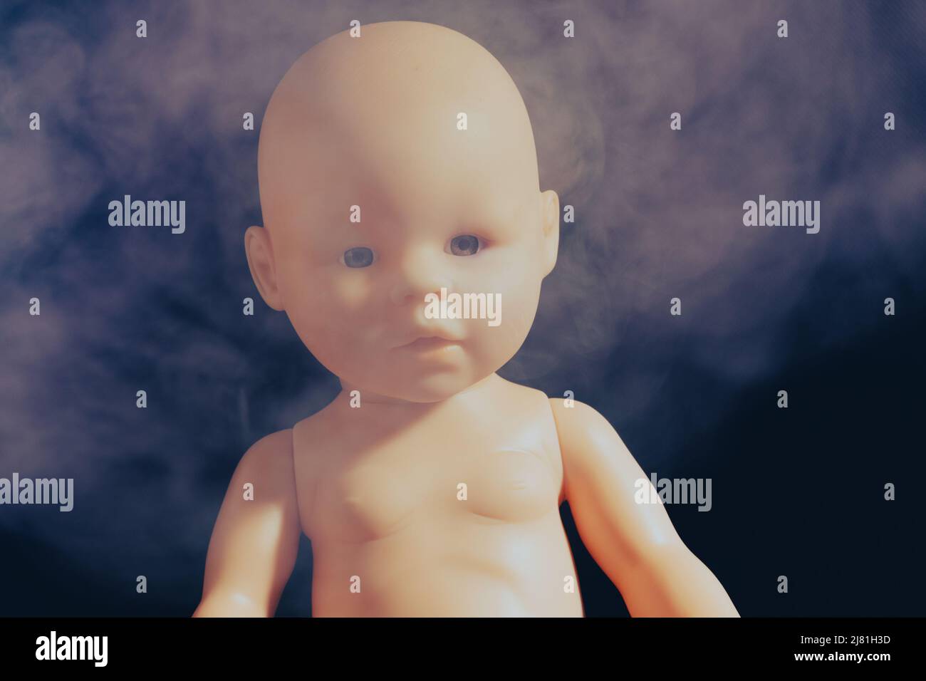 Baby Puppe in Rauch auf einem dunklen Hintergrund. Das Konzept des Rauchens in Gegenwart von Kindern. Hochwertige Fotos Stockfoto