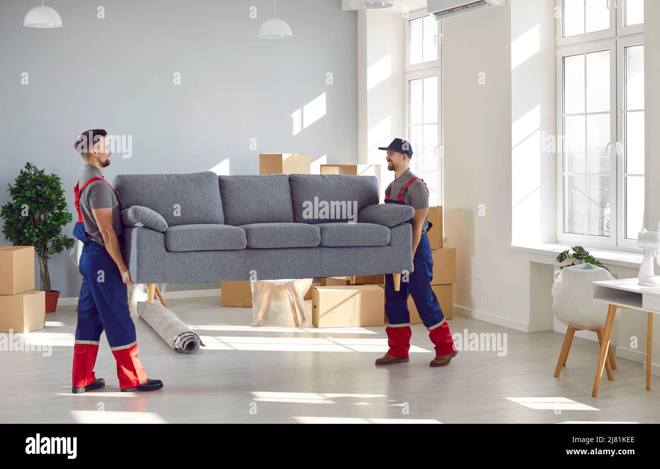 Männliche Lader nehmen das Sofa aus der Wohnung, während sie die Bestellung beim Umzugsdienst erfüllen. Stockfoto