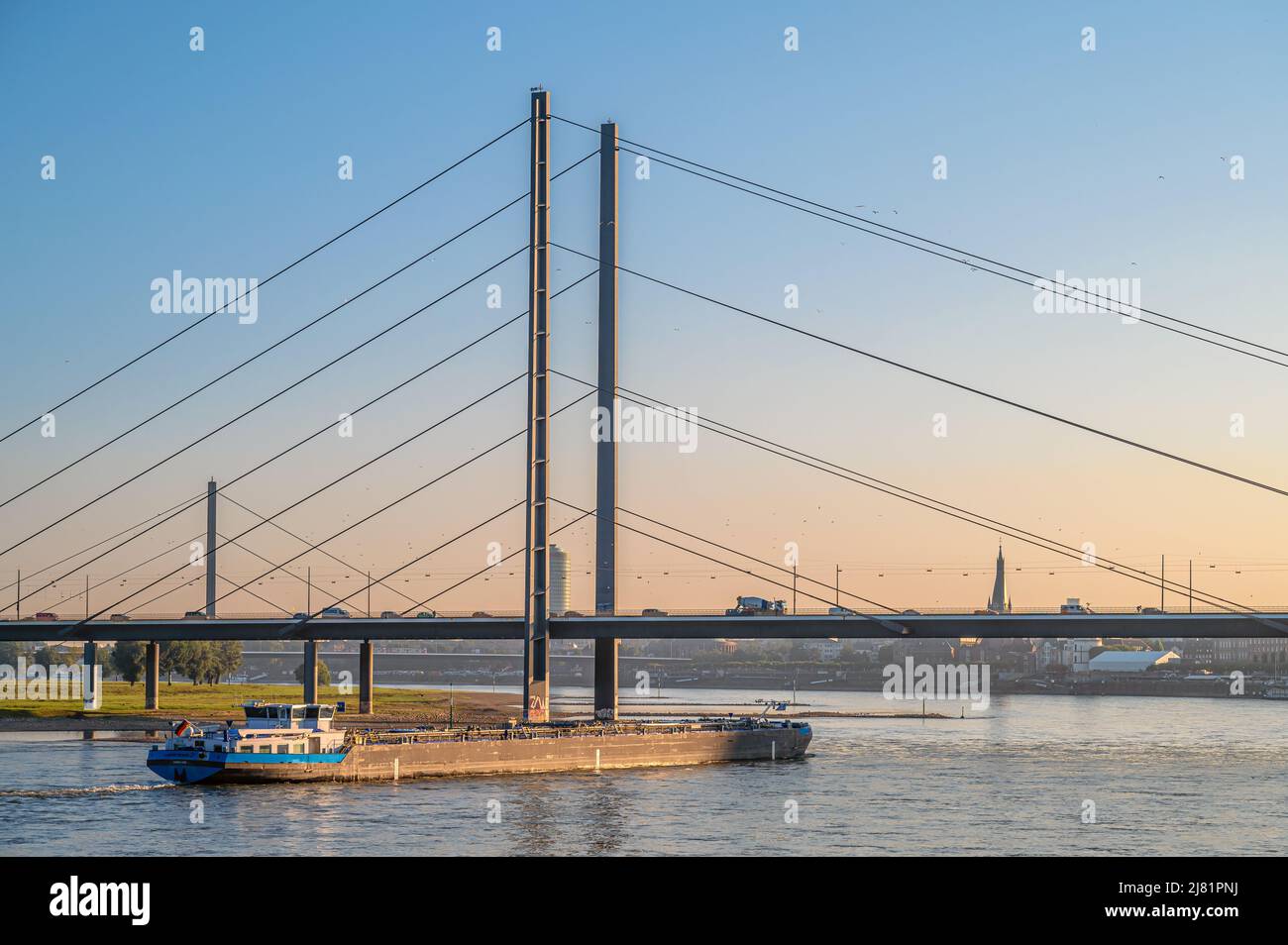 Binnenschiff vor der Düsseldorfer Rheinkniebrücke im Morgengrauen, NRW, Deutschland Stockfoto