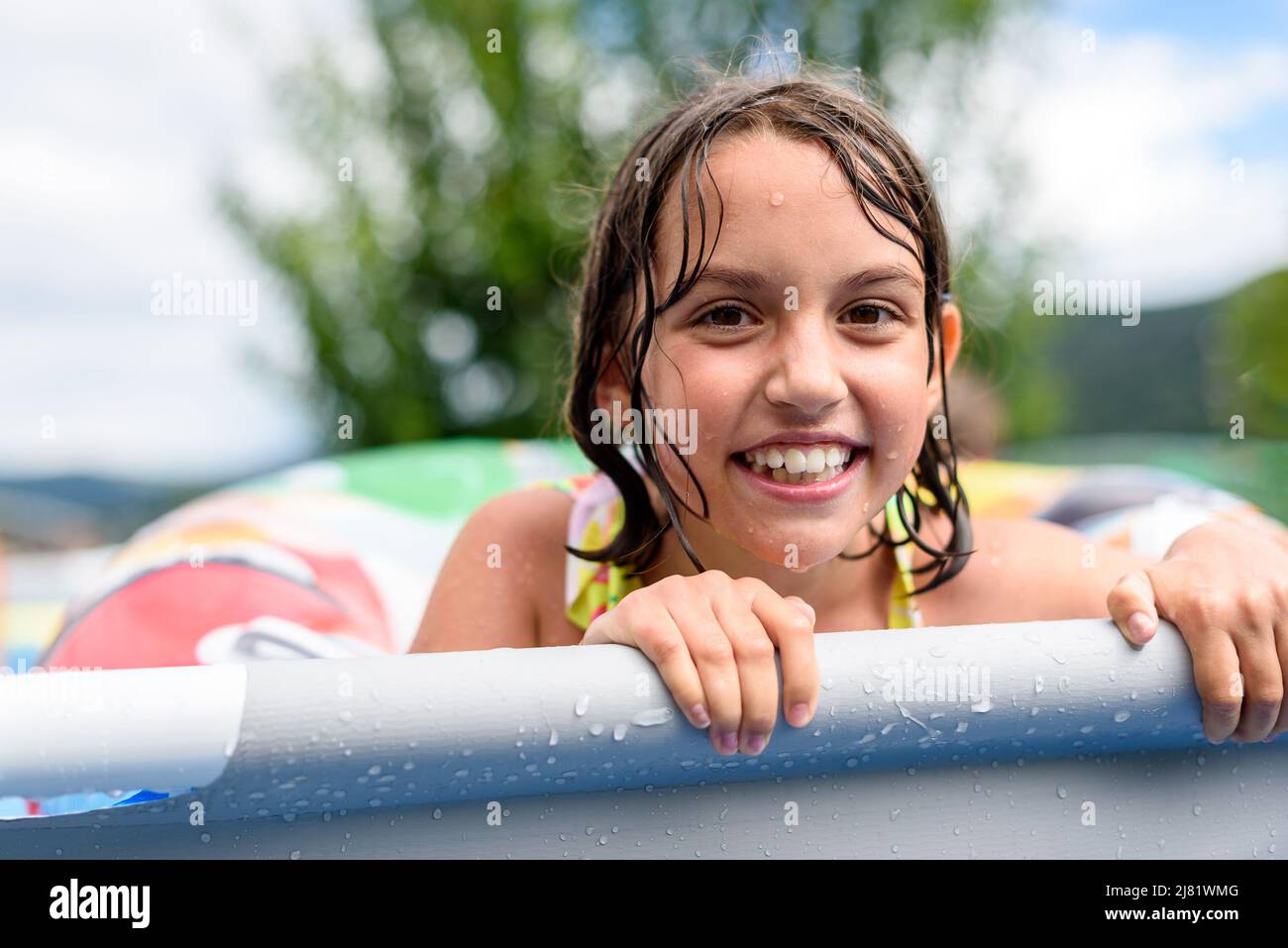 Kinder spielen im Sommer im heimischen Schwimmbad. Mädchen genießen Sommerurlaub im hinteren oder vorderen Hof Swimmingpool. Kinder spritzt Wasser Stockfoto