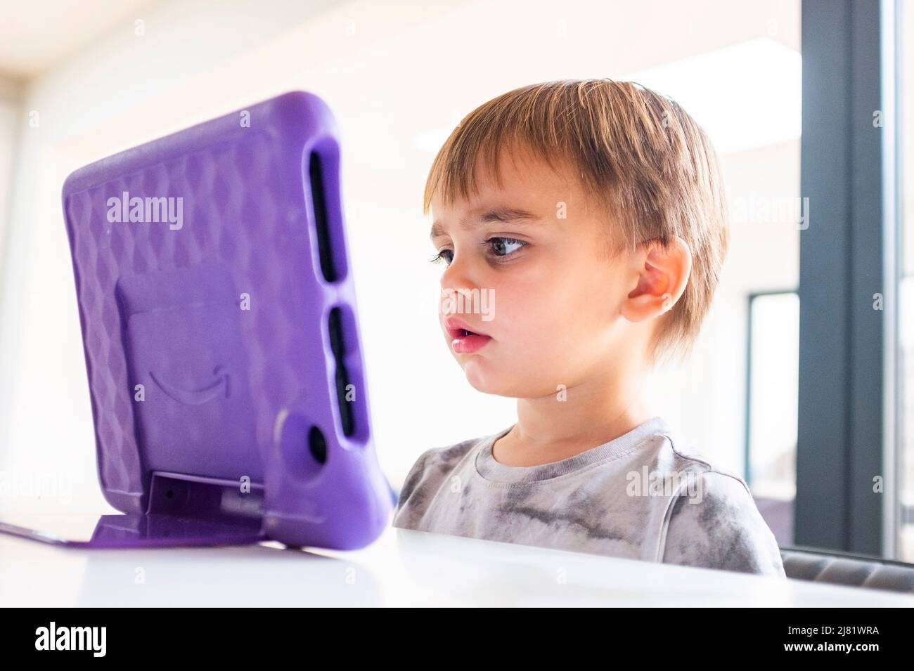 Kleiner, zweieinhalb Jahre alter Junge, der sich konzentriert, während er zu Hause einen Lerncomputer für Spielzeuge verwendet Stockfoto