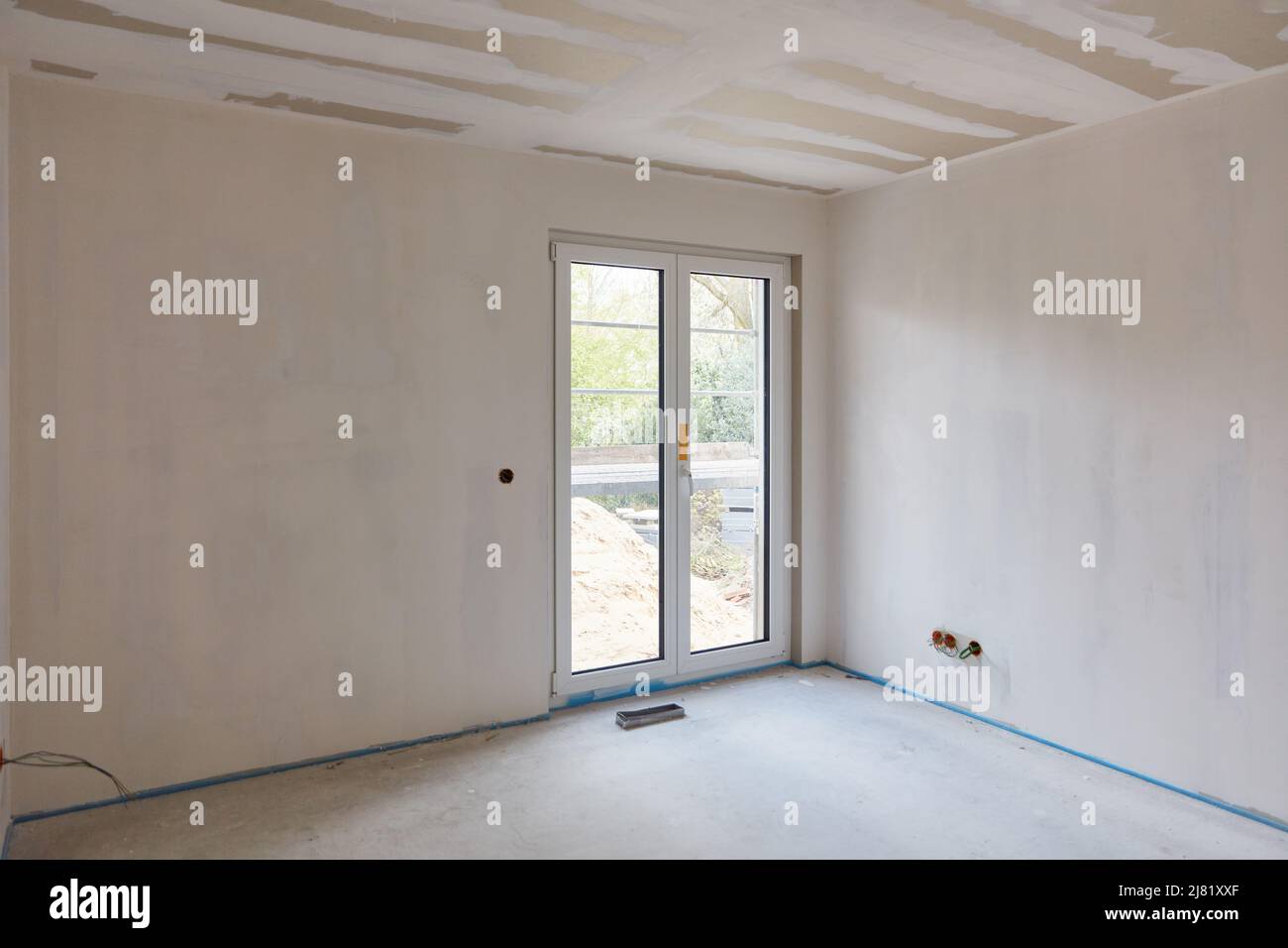 Verputzen und Füllen der Wände und Decken in einem Raum mit einer Terrassentür in einem Neubau Stockfoto