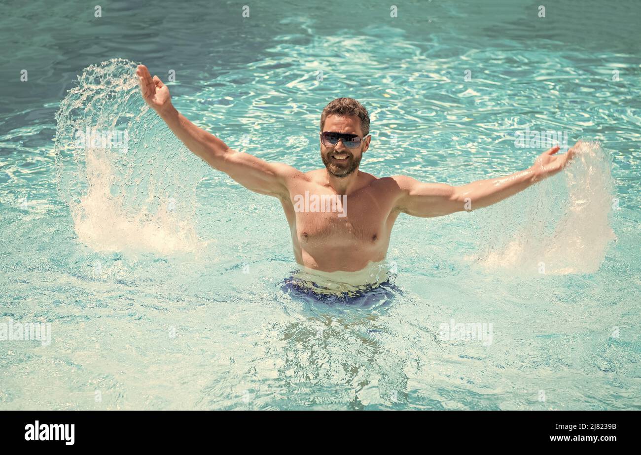 Poolparty. Sommerstimmung Konzept. Sommerurlaub. Kerl trägt Gläser im Wasser. Stockfoto