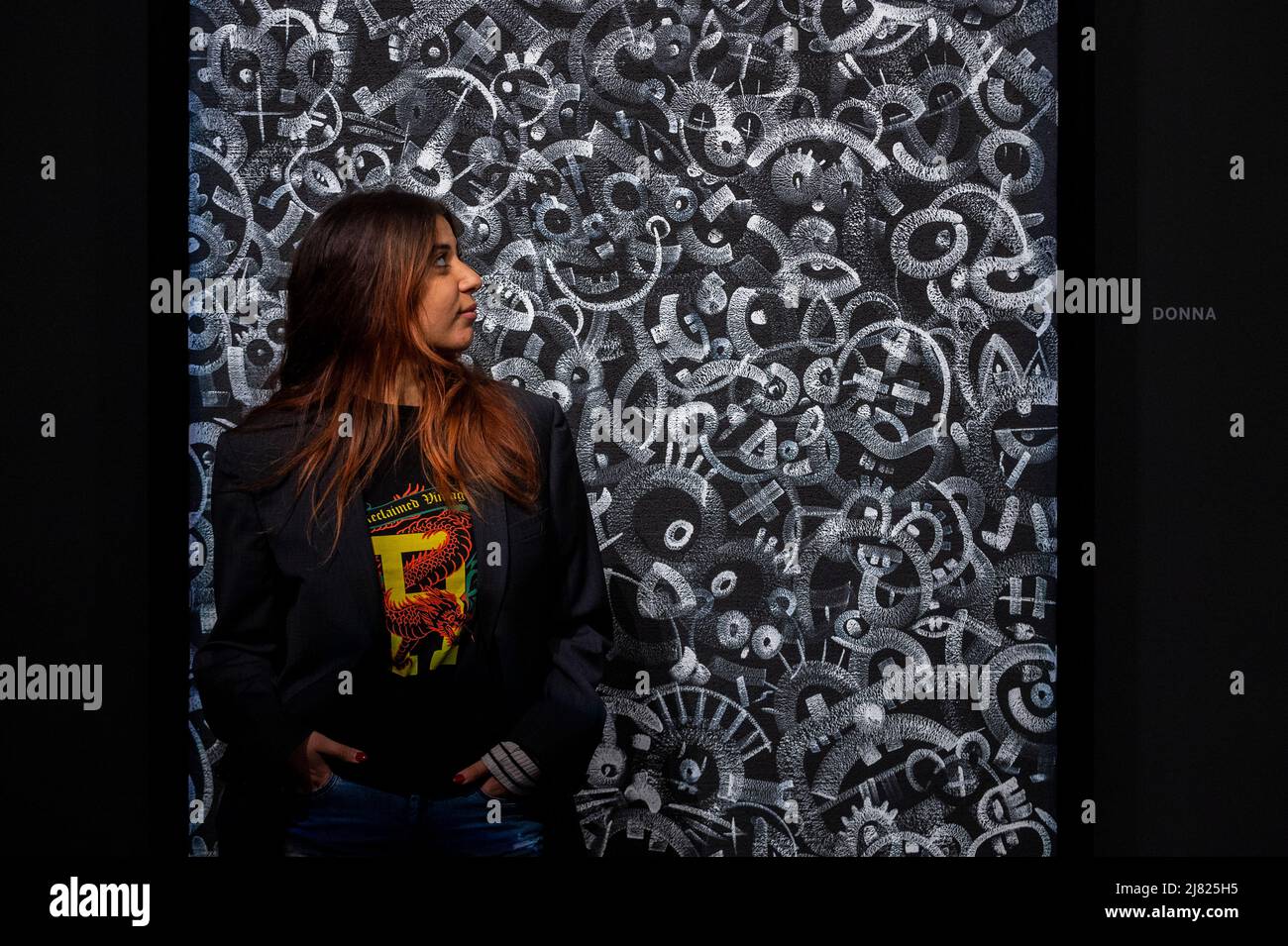 London, Großbritannien. 12 Mai 2022. Ein Mitarbeiter sieht „Donna“ von Robbie Williams und Ed Godrich bei der Vorschau von „Black and White Paintings“, einer Debütausstellung in Sothebys New Bond Street Galerien von Sänger Robbie Williams und seinem kreativen Partner Ed Godrich. 14 großformatige Werke werden vom 13. Bis 15. Mai 2022 während des London Gallery Weekends gezeigt und sind nach beliebten weiblichen Namen aus dem Jahr 1980s benannt. Kredit: Stephen Chung / Alamy Live Nachrichten Stockfoto