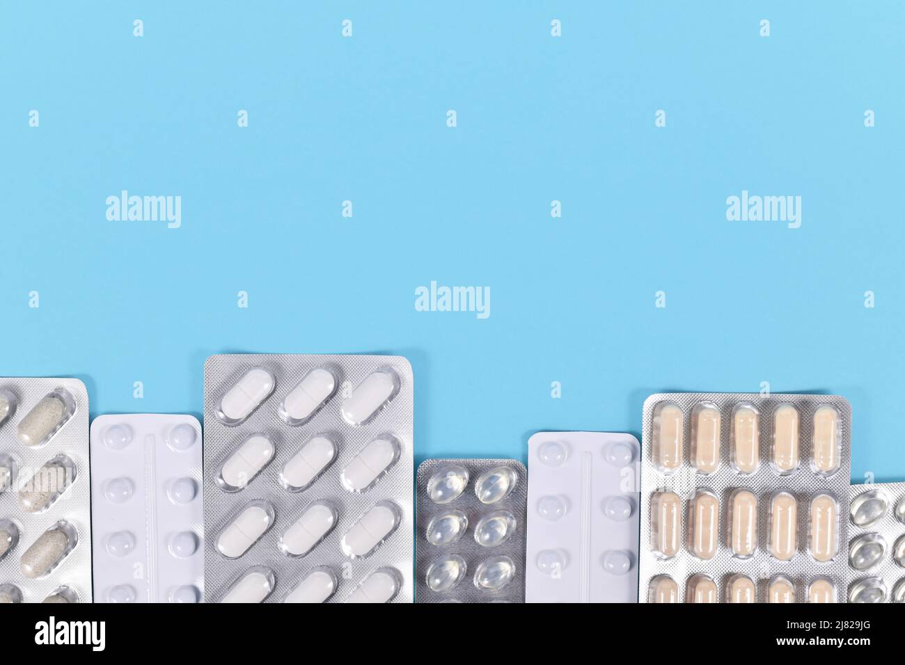 Blisterpackungen mit verschiedenen Pillen und Kapseln unten auf blauem Hintergrund mit Platz zum Kopieren Stockfoto