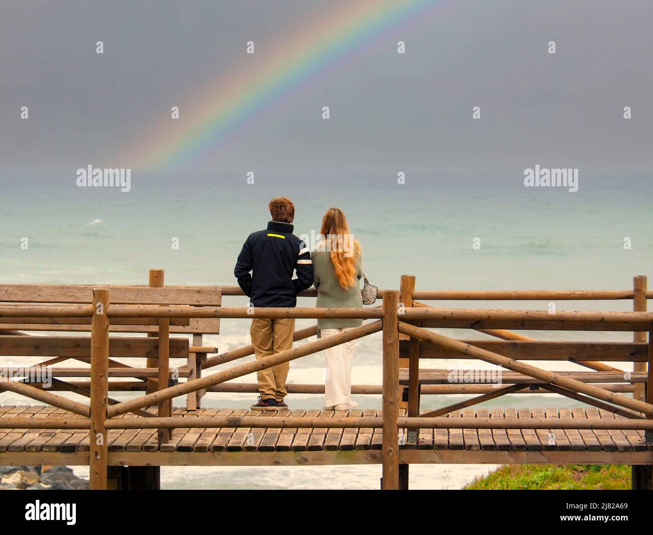 Ein heterosexuelles Paar, das einen Regenbogen vor dem Strand von Marbella betrachtet Stockfoto