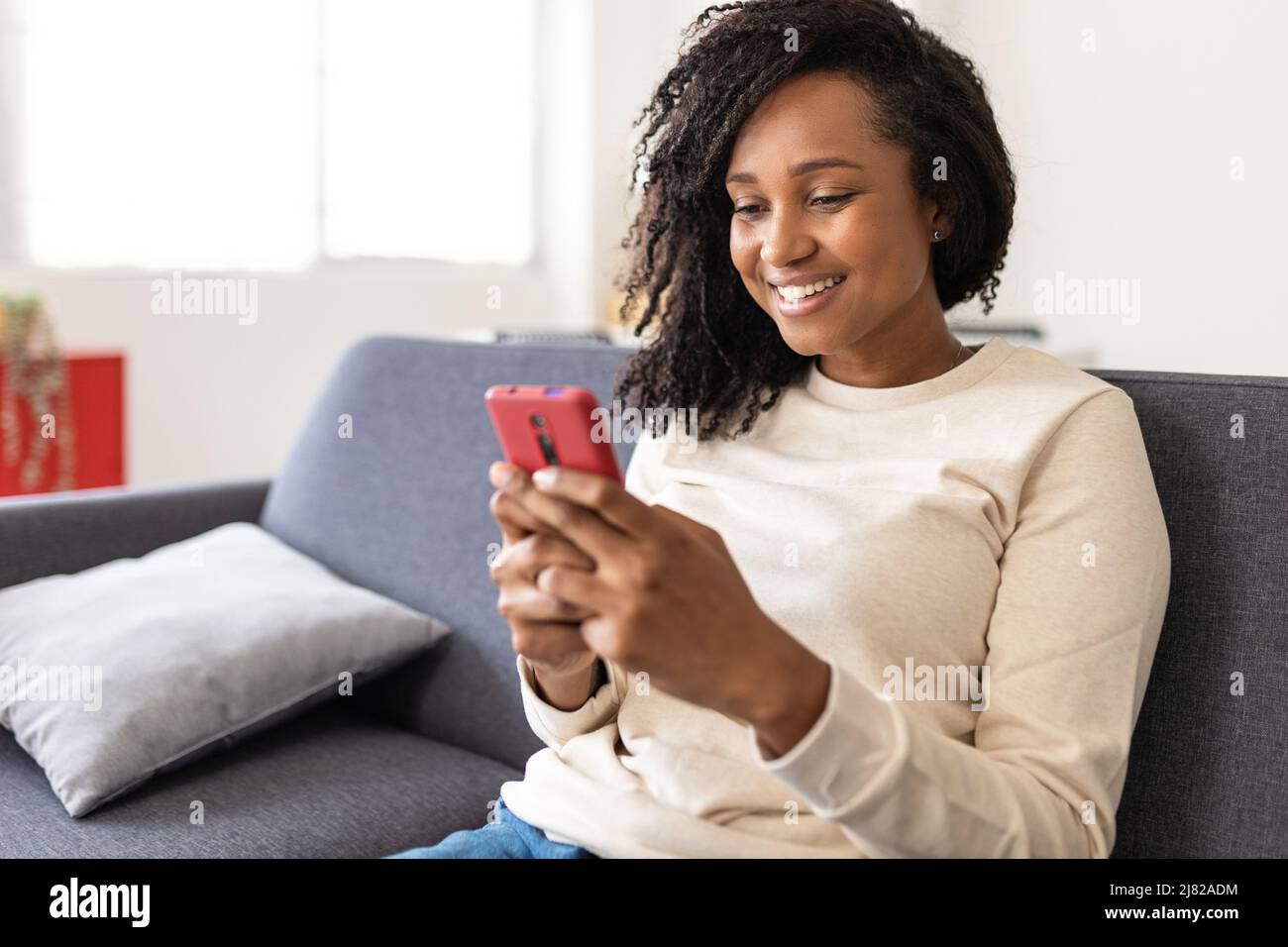 Gemischte Rasse junge Frau mit Smartphone-Handy zu Hause Stockfoto