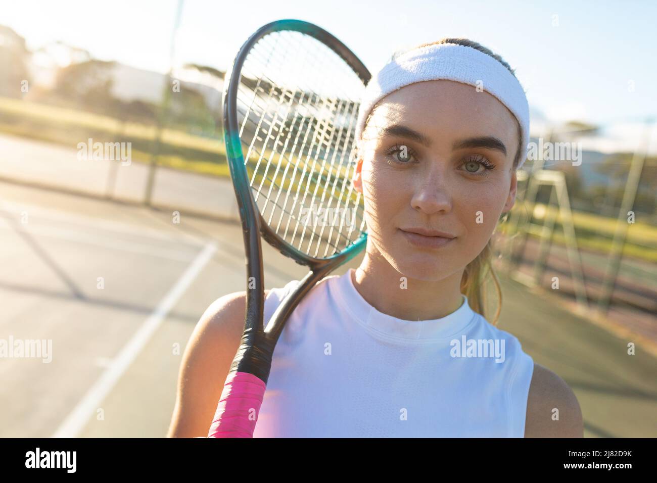 Porträt einer schönen jungen kaukasischen Tennisspielerin mit Stirnband und Schlägerplatz Stockfoto