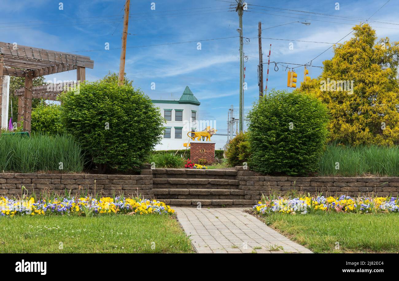 THOMASVILLE, NC, USA-8 MAY 2022: Lions Club Icon sichtbar aus einem kleinen Park, Gehweg mit Blumen gesäumt. Stockfoto