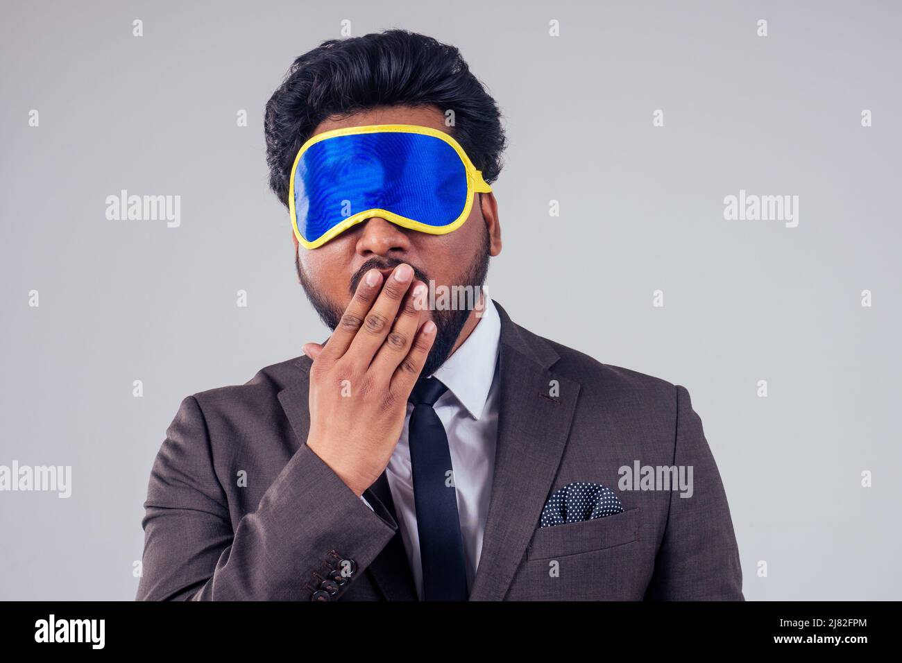 Reisender inder Business-Mann trägt stilvolle klassische Anzug und Schlafmaske im Studio weißen Hintergrund Stockfoto