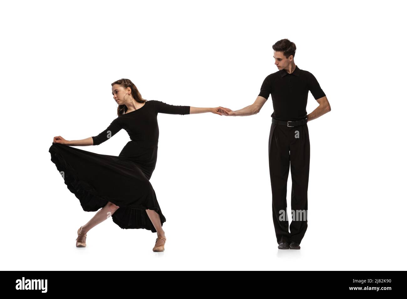 Dynamisches Porträt von jungen, gefühlvollen Tänzern in schwarzen Outfits, die auf weißem Hintergrund den Tanz im Ballsaal tanzen. Konzept von Kunst, Schönheit, Musik, Stil. Stockfoto