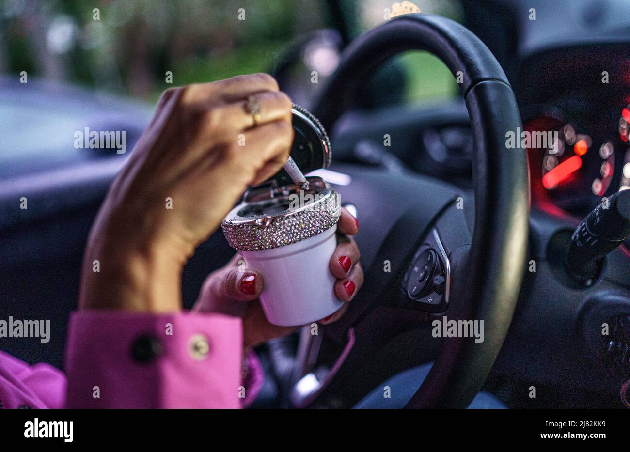 11. Mai 2022, Schleswig-Holstein, Flensburg: Eine Frau stutzt hinter dem Steuer ihres Autos eine Zigarette in einen Aschenbecher. Foto: Axel Heimken/dpa Stockfoto