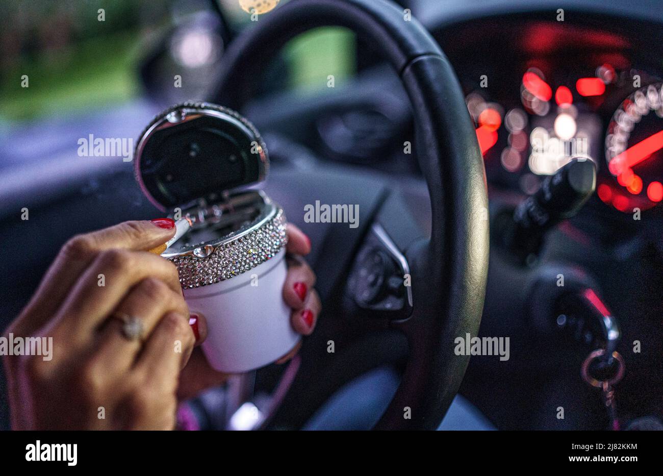 11. Mai 2022, Schleswig-Holstein, Flensburg: Eine Frau stutzt hinter dem Steuer ihres Autos eine Zigarette in einen Aschenbecher. Foto: Axel Heimken/dpa Stockfoto