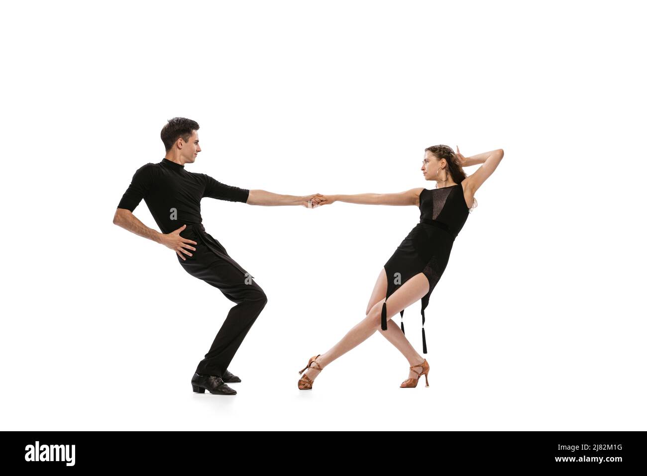 Dynamisches Porträt von jungen, gefühlvollen Tänzern in schwarzen Outfits, die auf weißem Hintergrund den Tanz im Ballsaal tanzen. Konzept von Kunst, Schönheit, Musik, Stil. Stockfoto