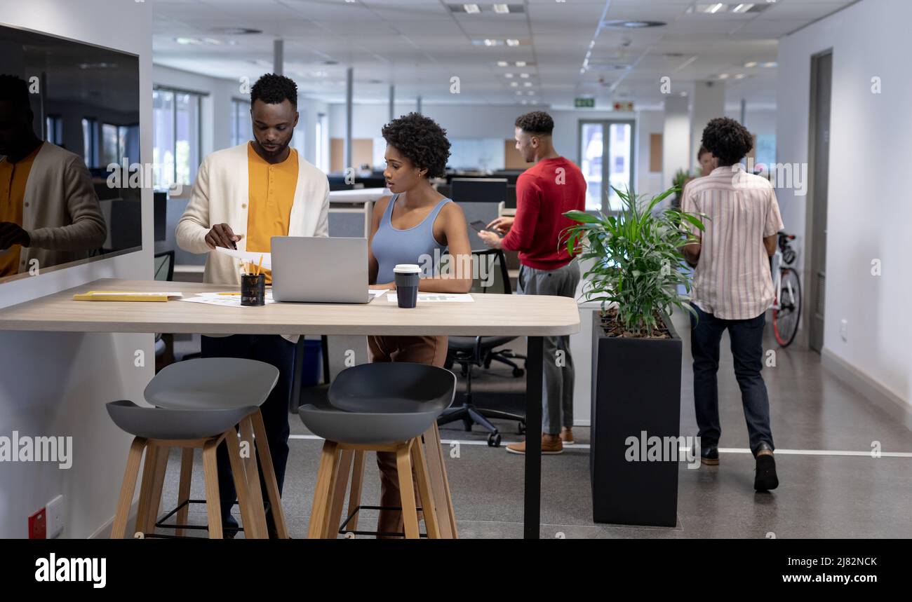 Junge afroamerikanische Unternehmensberater arbeiten zusammen, während sie mit einem Laptop am Arbeitsplatz stehen Stockfoto