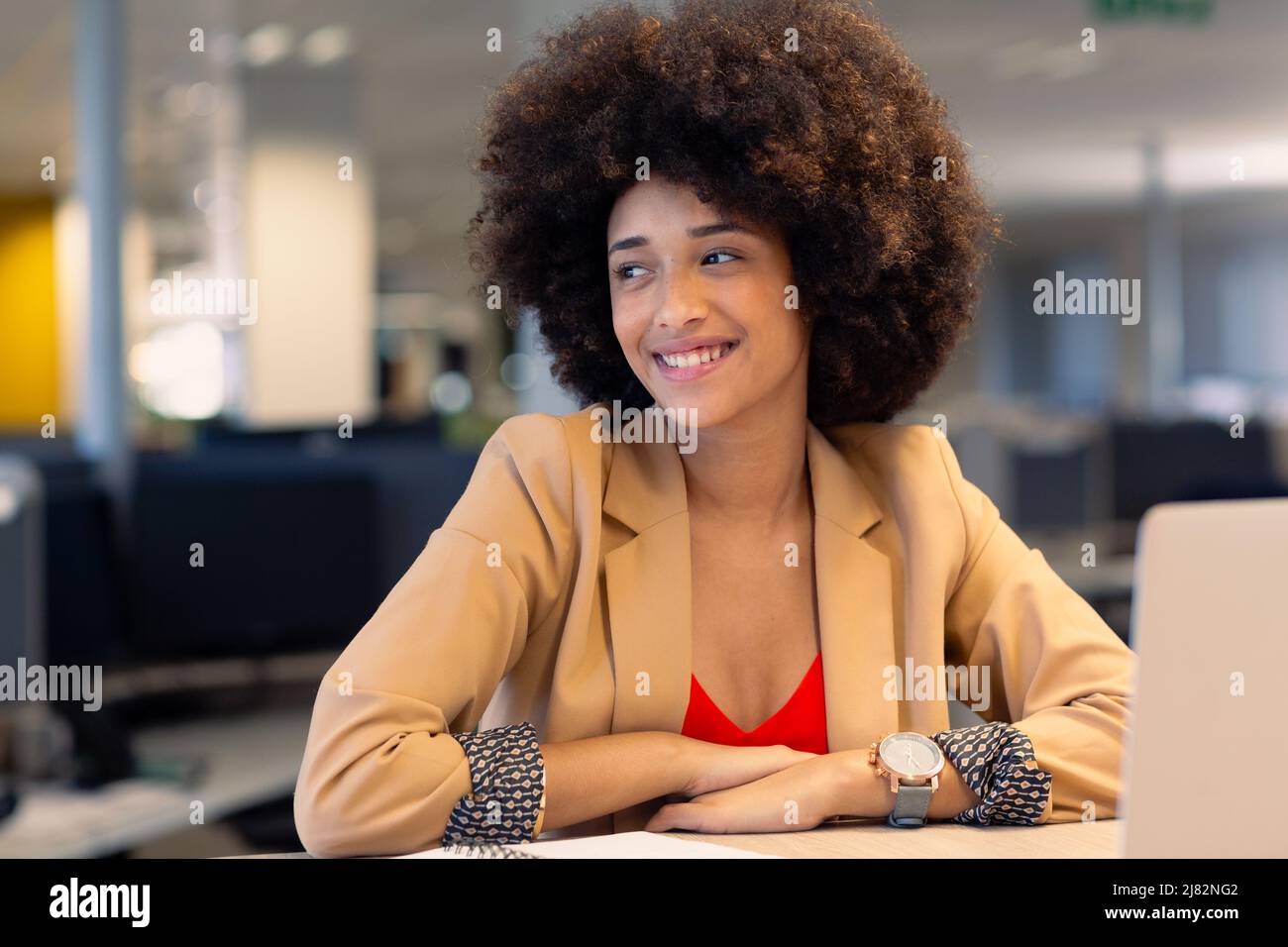 Glückliche junge schöne weibliche afroamerikanische Berater mit afro Frisur Blick weg am Arbeitsplatz Stockfoto