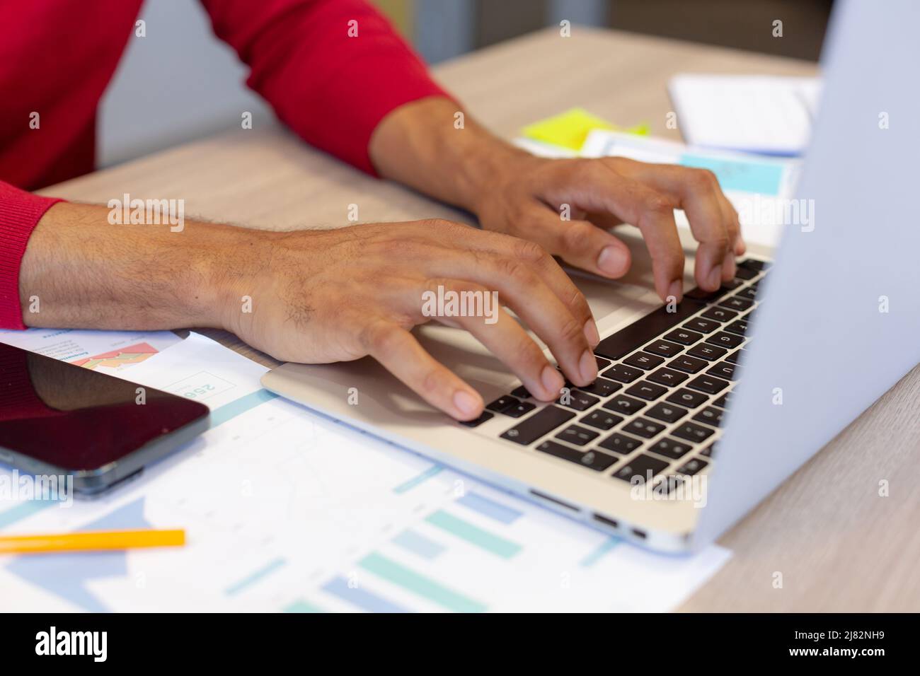 Mittelteil des hispanischen männlichen Beraters, der während der Arbeit am Arbeitsplatz auf der Laptop-Tastatur tippt Stockfoto