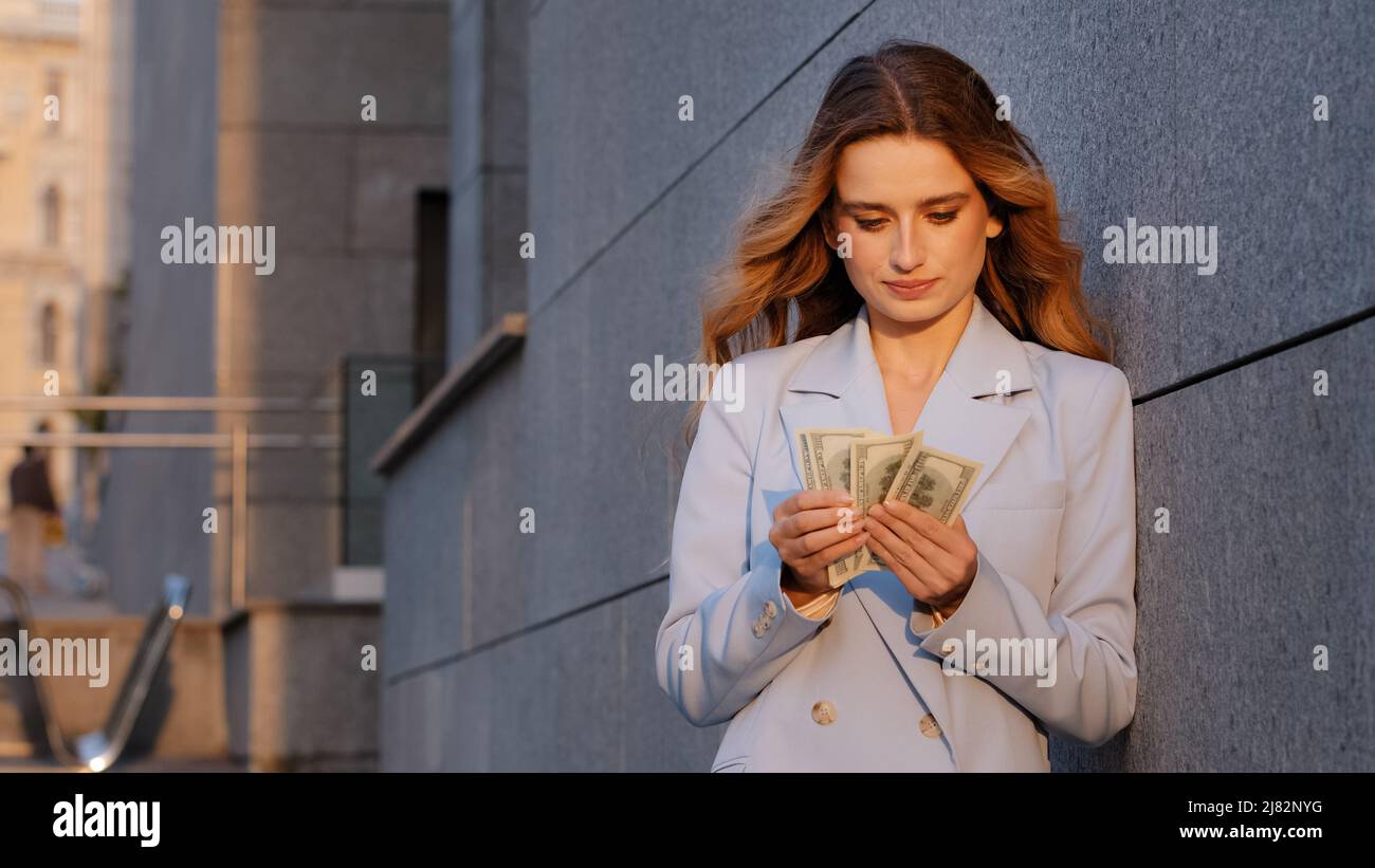 Erfolgreiche reiche kaukasische tausendjährige Geschäftsfrau auf der Straße Stadt im Freien Zählen Geld halten Dollar Banknoten Rechnung Budget zählen Gehalt Stockfoto