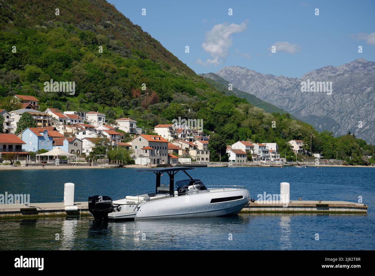 Kotor Bay, Montenegro. Ein Boot auf dem Meer und das Dorf Stoliv im Hintergrund. Stockfoto