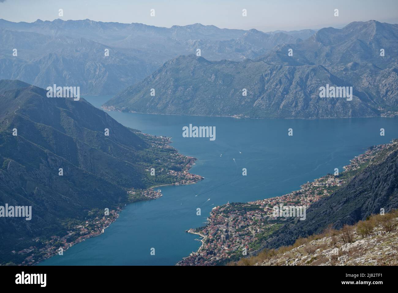 Blick auf die Bucht von Kotor, Montenegro. Dörfer und die Stadt Kotor am Rande des Meeres mit dramatischen umliegenden Bergen. Stockfoto