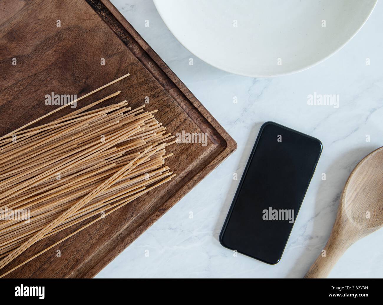 Kochen mit Vollkornpasta und Smartphone für Anweisungen Stockfoto