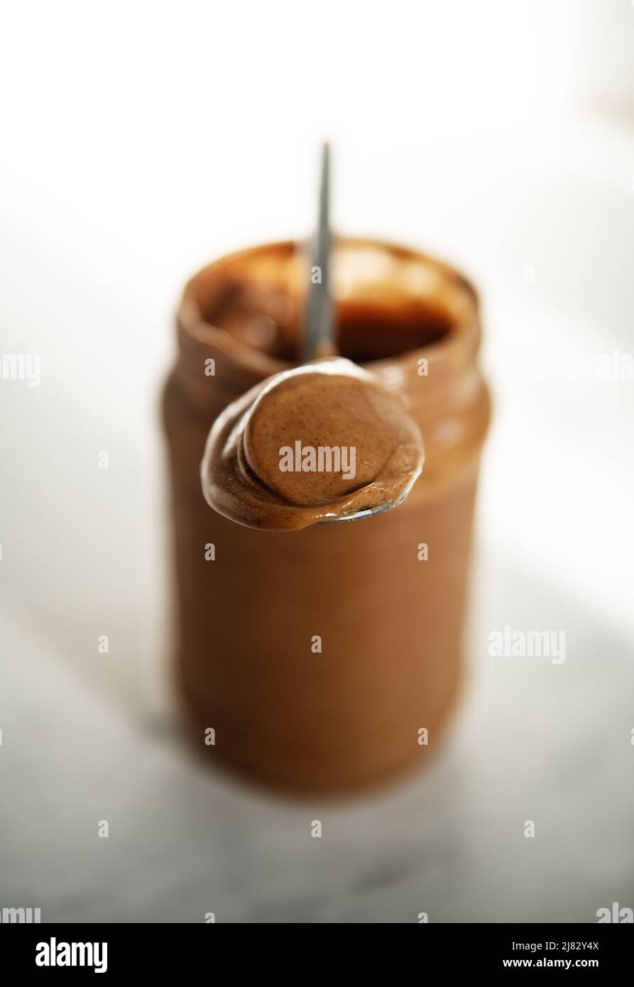 Löffel und Behälter mit Nussbutter Stockfoto