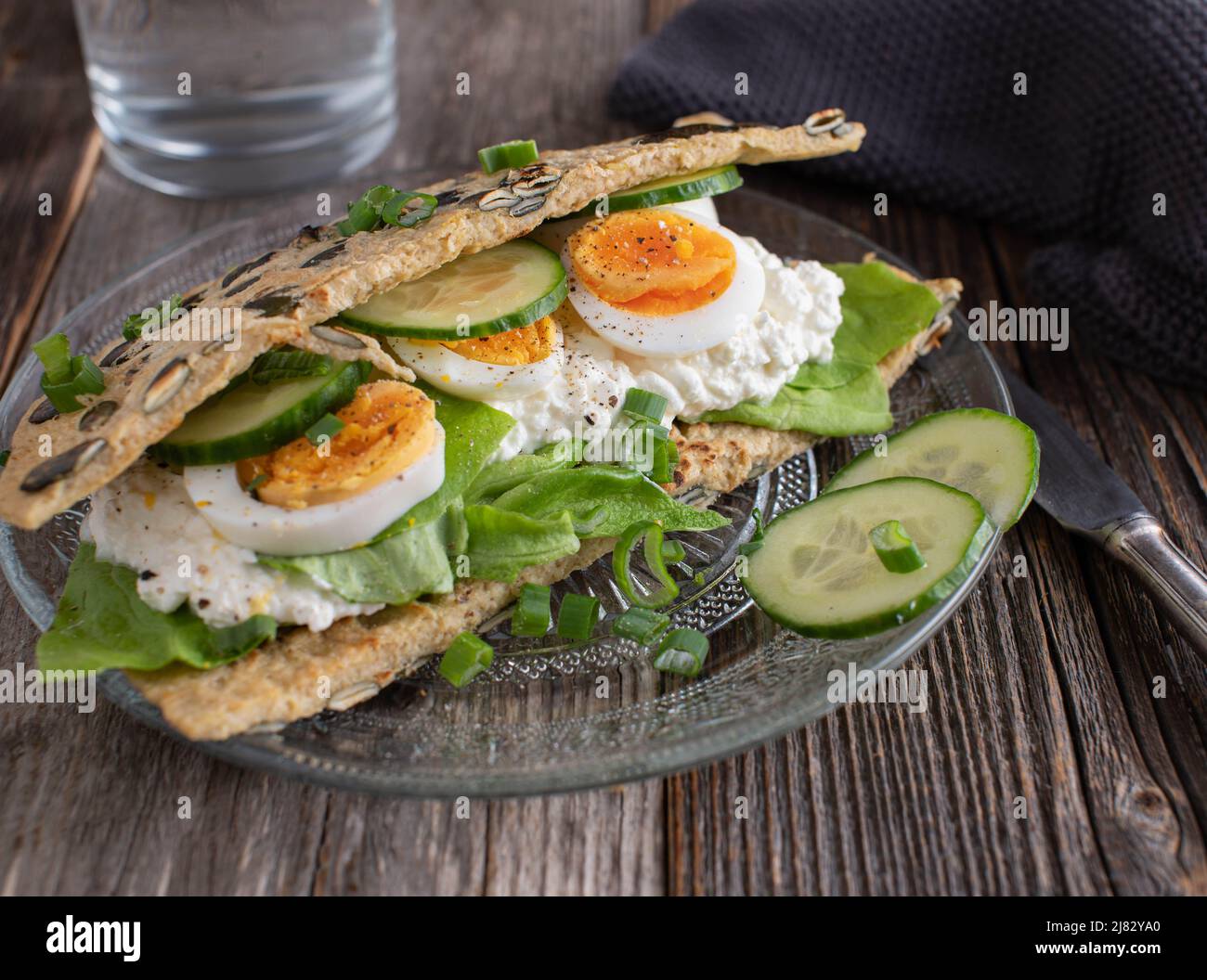 Proteinreiches Sandwich mit einem Haferflocken-Pfannkuchen, gefüllt mit Quark, gekochten Eiern und Gemüse. Stockfoto