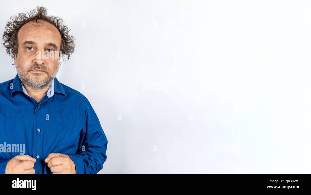 Wütend oder verwirrt aussehende Mann verrückt Wissenschaftler Typ mit blauen Mann Hemd und wilden Haaren vor hellweißem Hintergrund Stockfoto