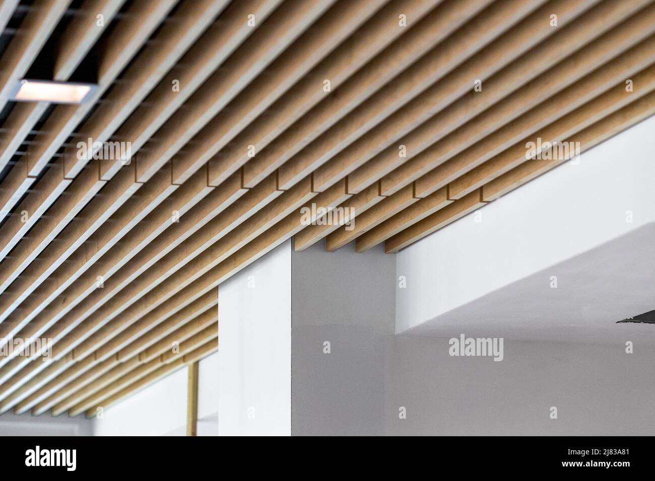 Installation von schalldämmenden Holzplanken zur visuellen Dekoration und Lärmreduzierung in einem neu errichteten Geschäftsgebäude Stockfoto