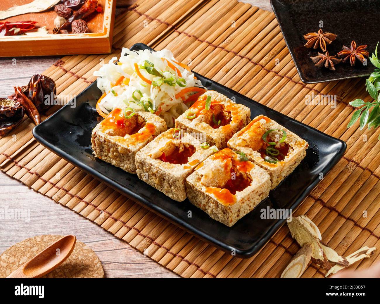 Knusprig gebratener Stinky Tofu in einem schwarzen Tablett mit rotem Chili isoliert auf matter Seitenansicht japanischer Speisen Stockfoto