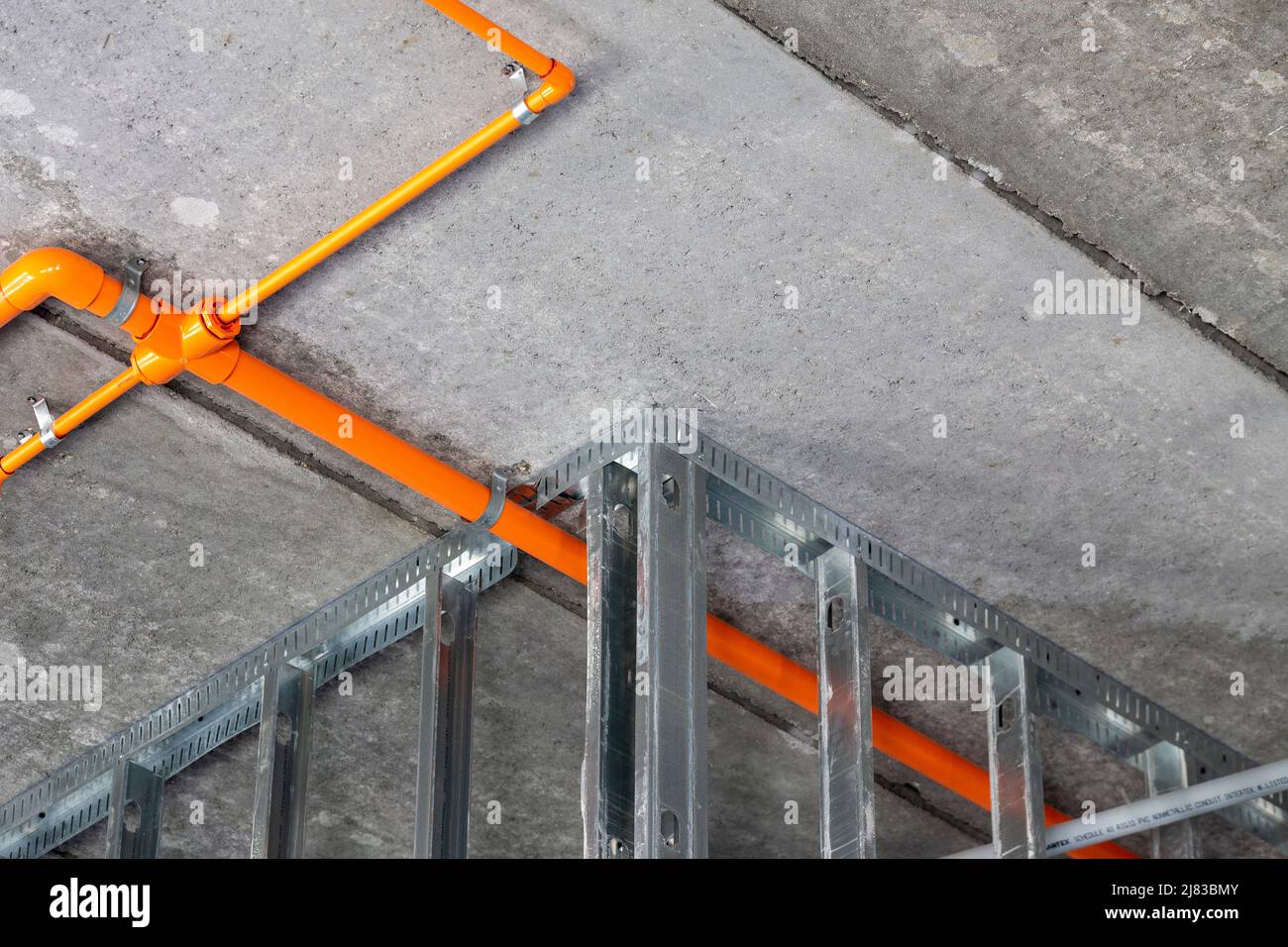 Sprinklerrohre zwischen verzinktem Stahlrahmen an der Decke eines im Bau befindlichen mehrstöckigen Hotelzimmers. Stockfoto