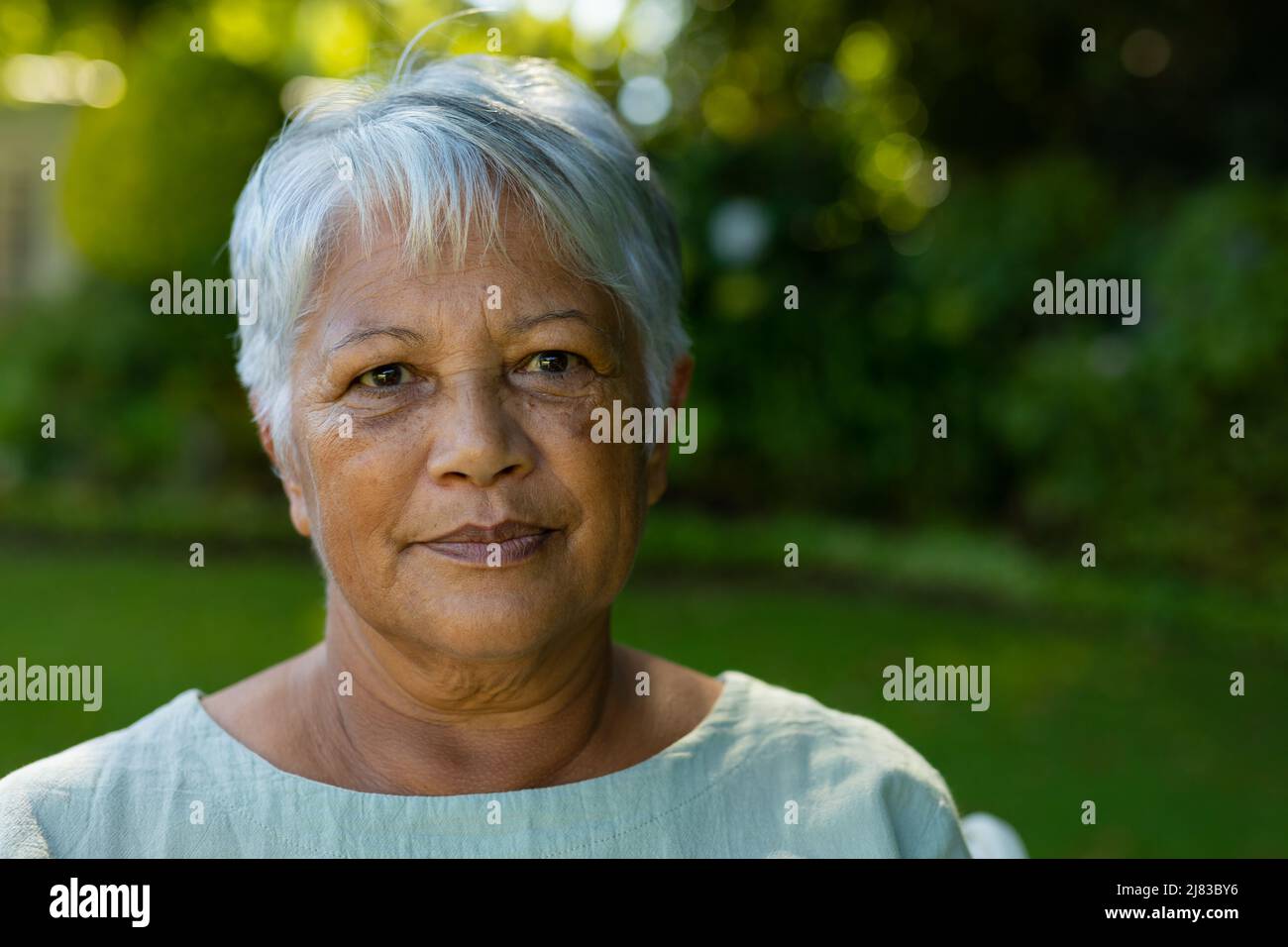 Nahaufnahme des Porträts einer selbstbewussten Senioren aus der Bira mit kurzen grauen Haaren gegen Pflanzen im Park Stockfoto