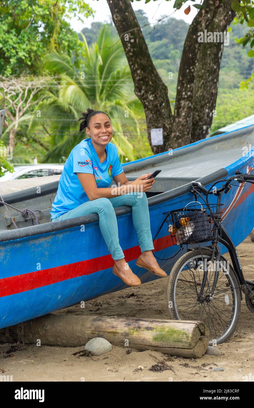 Junge Frau, die auf einem Fischerboot sitzt, Chino Beach, Puerto Viejo de Talamanca, Provinz Limón, Republik Costa Rica Stockfoto
