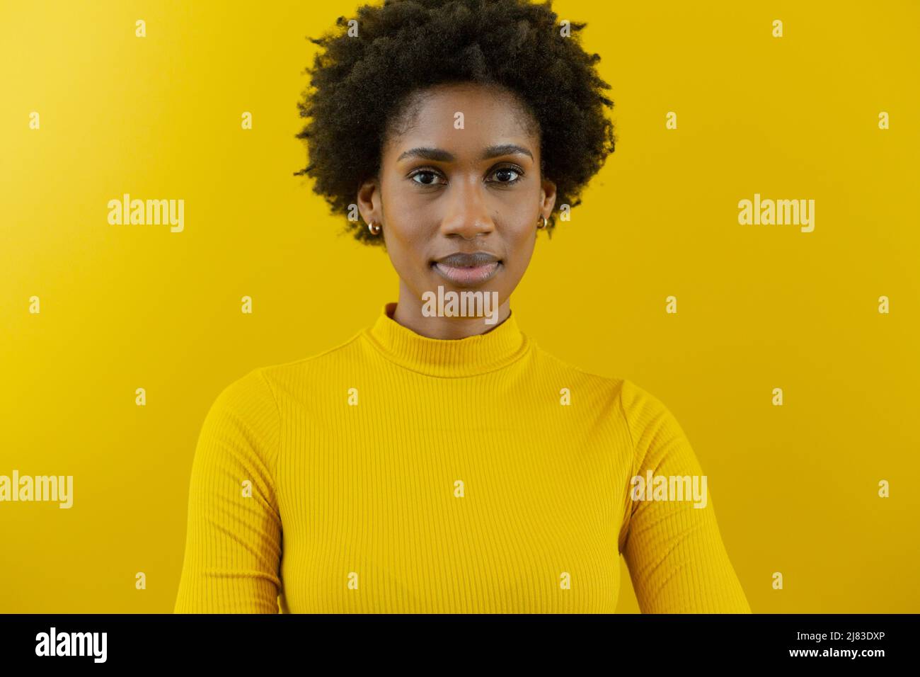 Porträt einer selbstbewussten jungen afroamerikanischen Berater-Frau mit Afro-Frisur an der gelben Wand Stockfoto