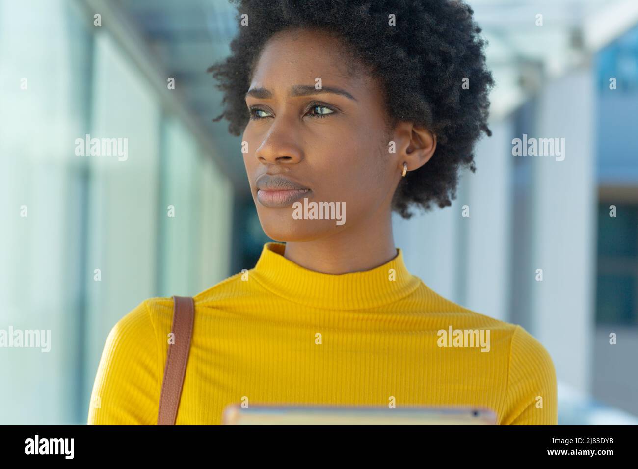 Nachdenkliche afroamerikanische junge Geschäftsfrau mit Afro-Frisur, die am Arbeitsplatz absieht Stockfoto