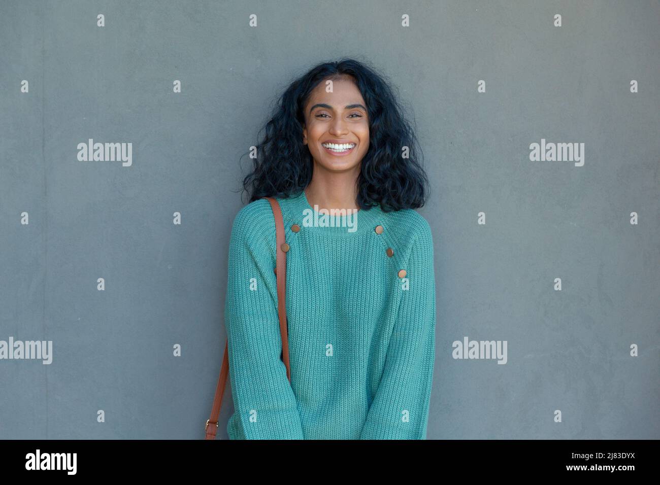 Porträt einer glücklichen jungen biracial Geschäftsfrau, die an einer grauen Wand mit Kopierraum steht Stockfoto