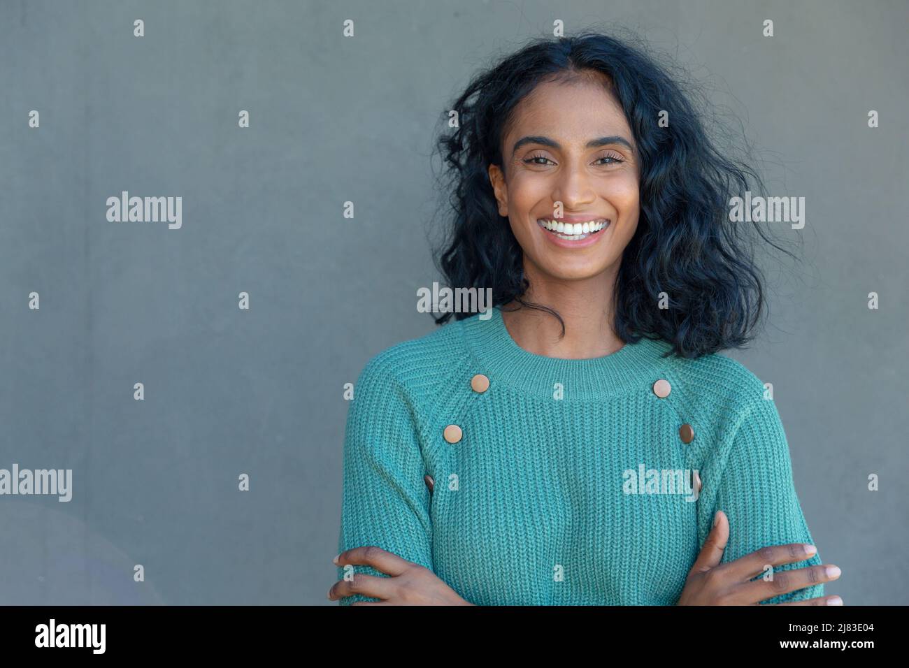 Porträt einer glücklichen biracial junge weibliche Berater mit Armen gekreuzt von copy Raum auf graue Wand Stockfoto