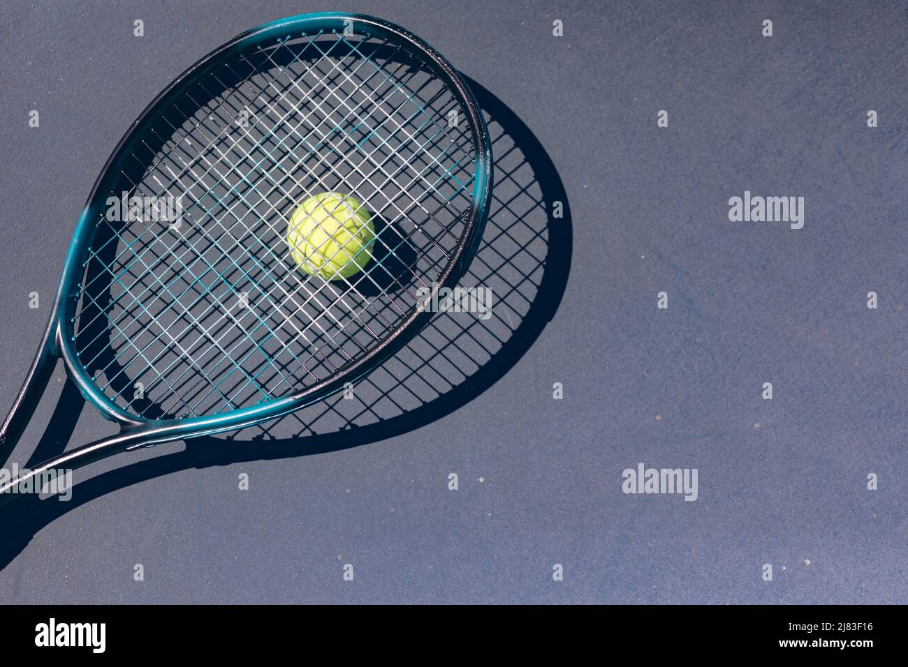 Direkt über der Ansicht des Tennisschlägers auf dem Ball über dem grauen Platz während des sonnigen Tages Stockfoto