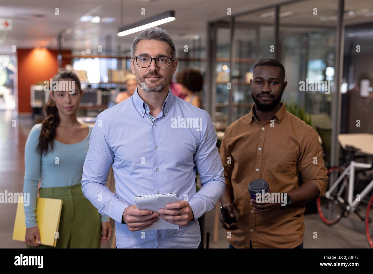 Porträt selbstbewusster, multirassischer Unternehmensberater, die am modernen Arbeitsplatz zusammenstehen Stockfoto