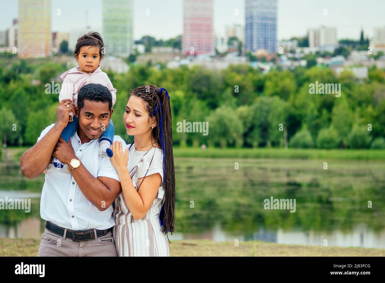 Transnationale interrassische Mutter und Vater, die mit ihrem gemischten Mädchen im Herbstpark spazieren gehen Stockfoto