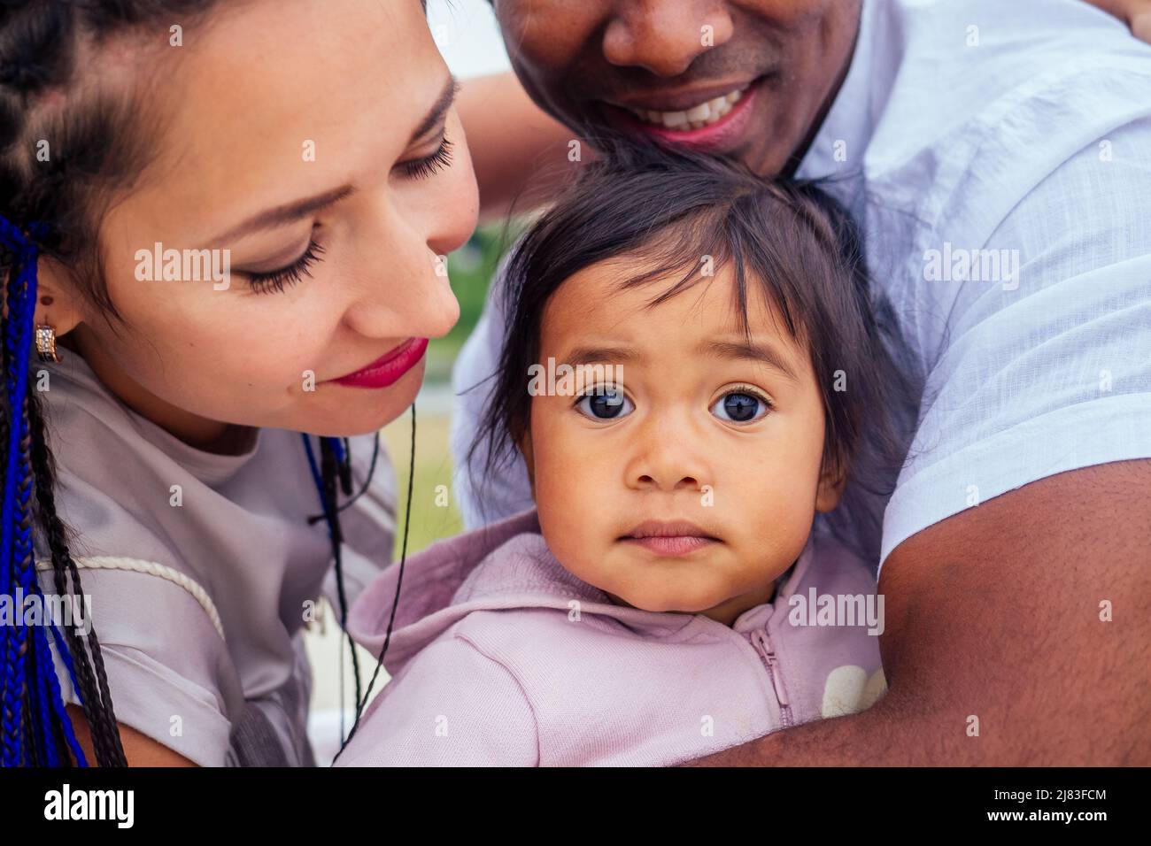 Transnationale interrassische Mutter und Vater, die mit ihrem gemischten Mädchen im Herbstpark spazieren gehen Stockfoto
