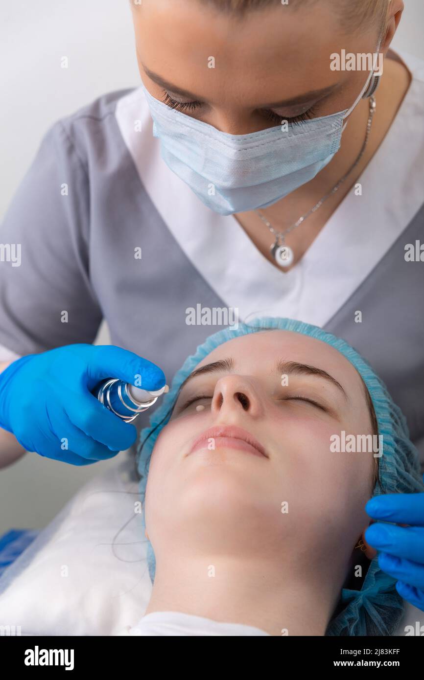 Gesichtshautcreme Behandlung oder Therapie für müde Gesichtshaut. Dermatologe, der Creme auf die weibliche Gesichtshaut anwendet. Stockfoto