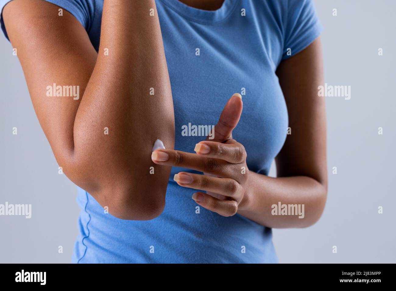Mittelteil einer afroamerikanischen mittleren erwachsenen Frau, die Salbe auf den Unterarm aufgetragen hat, Raum kopieren Stockfoto