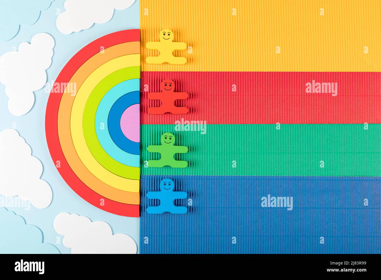 Konzept zum Internationalen Kindertag. Regenbogen mit Holzspielzeug von Kindern auf dem blauen Hintergrund. Flach liegend. Speicherplatz kopieren. Stockfoto