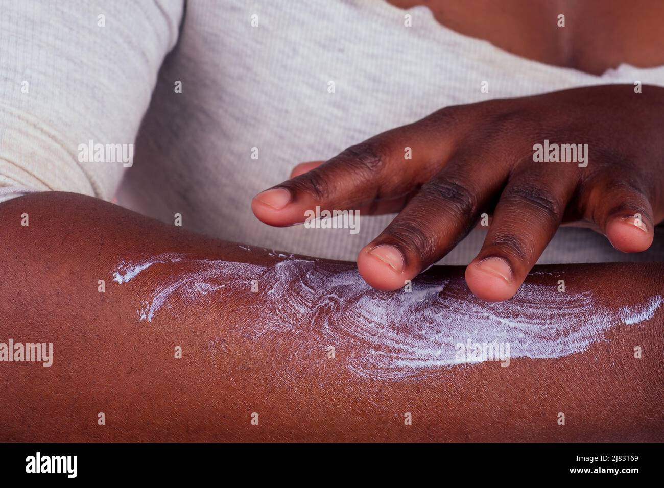 afroamerikanische Frau, die Creme-Shooting zwischen zwei Produkten in Studio rosa Hintergrund Stockfoto