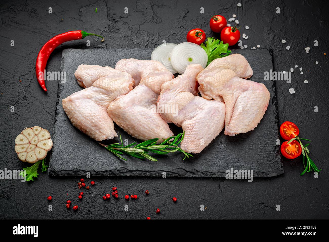 Rohe Hähnchenflügel auf einem schwarzen Küchentisch. Gesundes Lebensmittelkonzept. Stockfoto
