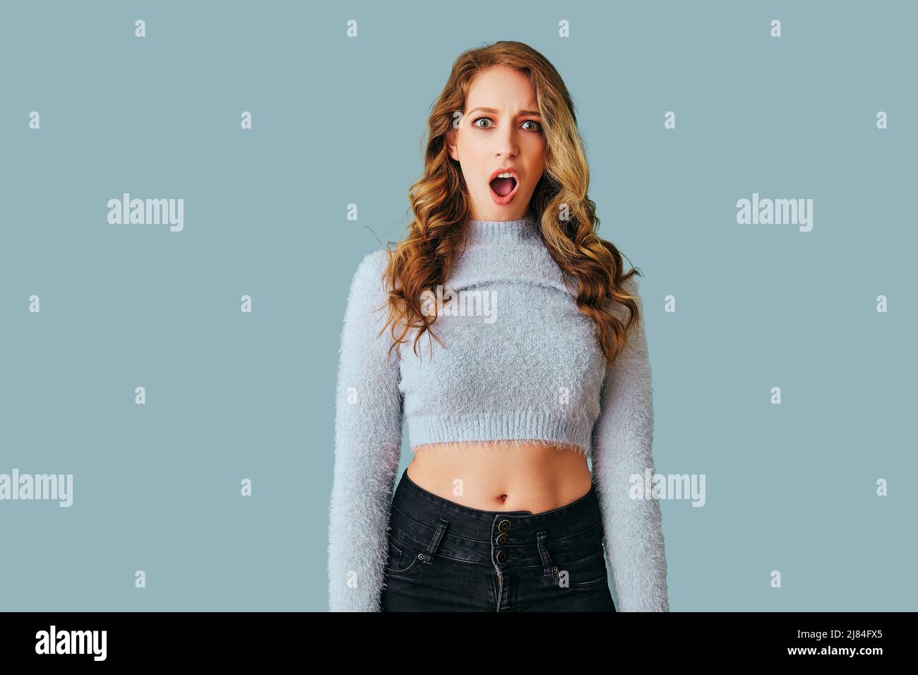 Porträt eines jungen Erwachsenen schockiert Frau mit langen lockigen Haaren Blick auf Kamera-Studio Stockfoto